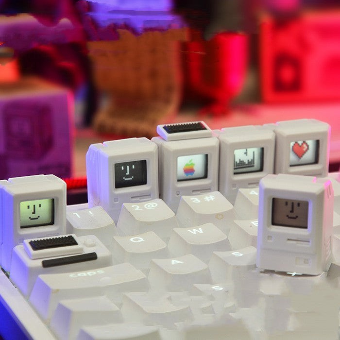 Clackycharm Macintosh retro artisan keycaps in wit met iconische computerontwerpen op een mechanisch toetsenbord